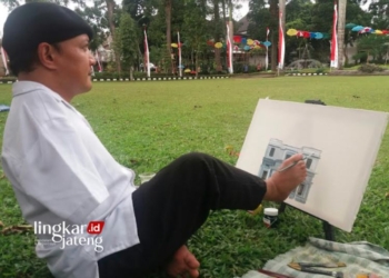 MELUKIS: Seniman Lukis, Sabar Subadri melukis dengan kaki. (Angga Rosa/Lingkarjateng.id)