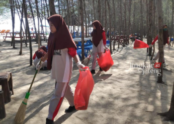 KERJA BAKTI: Siswa SMPN 1 Sulang membawa sapu dan kantong plastik untuk membersihkan sampah daun maupun plastik di area wisata Pantai Pasir Putih Wates. (R.Teguh Wibowo/Lingkarjateng.id)