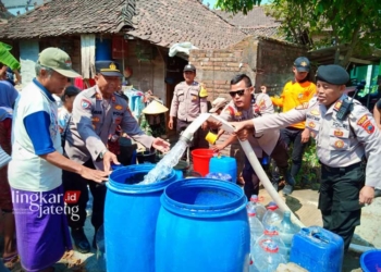 GOTONG ROYONG: Personel Polres Kudus menyalurkan bantuan air bersih di Desa Glagahwaru, Kecamatan Undaan, Kabupaten Kudus. (Ihza Fajar/Lingkarjateng.id)