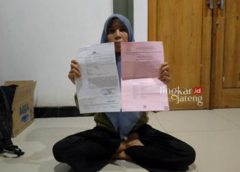 CARI KEADILAN: Lasni, istri Rofiul Amri menunjukkan surat penangkapan suaminya yang ditahan di Mapolres Rembang karena tuduhan pencurian kayu. (Dok. Lingkarjateng.id)