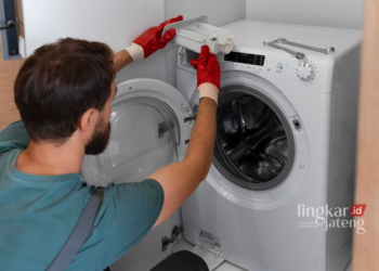 Ilustrasi orang yang membersihkan mesin cuci. (Freepik/Lingkarjateng.id)