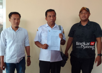 TIDAK TERIMA: Suraji (tengah) menunjukkan surat pemecatan terhadap dirinya dari Sekretaris Desa Asemrudung, Kecamatan Geyer, Kabupaten Grobogan. (Eko Wicaksono/Lingkarjateng.id)