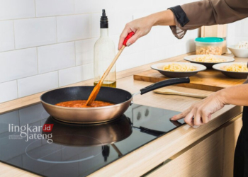 Ilustrasi orang yang memasak menggunakan kompor listrik. (Freepik/Lingkarjateng.id)