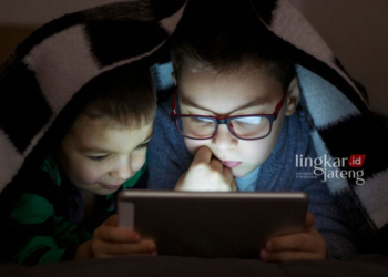 Ilustrasi anak yang bermain tablet. (Freepik/Lingkarjateng.id)