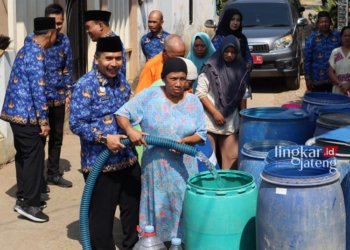SALURKAN BANTUAN: Ketua Dewan Pengurus Korpri Jepara Edy Sujatmiko saat membantu warga menampung bantuan air bersih. (Muslichul Basid/Lingkarjateng.id)