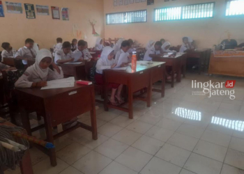 TETAP FOKUS: Siswa-siswa SDN Muktiharjo Lor mengerjakan Penilaian Akhir Semester (PAS) di ruang kelas yang dipenuhi genangan air, Selasa, 28 November 2023. (Rizky Syahrul/Lingkarjateng.id)