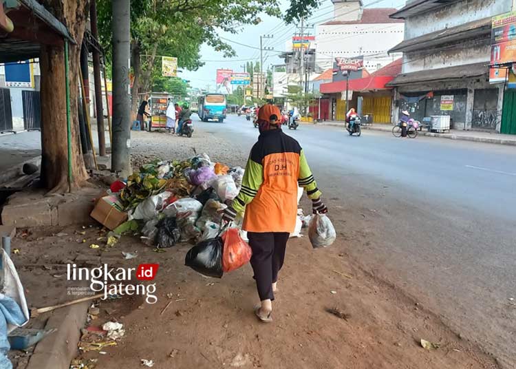 BERSIH-BERSIH: Petugas kebersihan Dinas Lingkungan Hidup Kabupaten Kendal sedang membersihkan sampah di area Taman Kota Weleri, Kendal pada Selasa, 14 November 2023. (Arvian Maulana/Lingkarjateng.id)