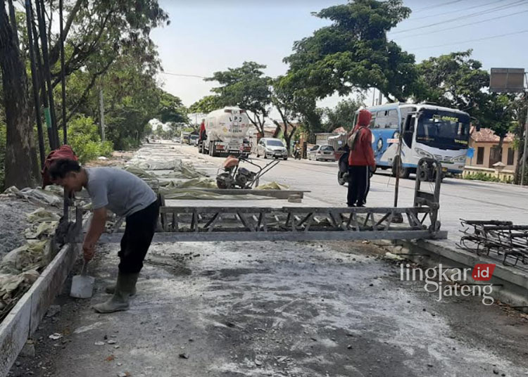 TERUS BERLANJUT: Pekerja melakukan pekerjaan untuk proses pembetonan jalan Pantura sekitar Clangapan bagian selatan, Kabupaten Rembang, Selasa, 21 November 2023. (R. Teguh Wibowo/Lingkarjateng.id)