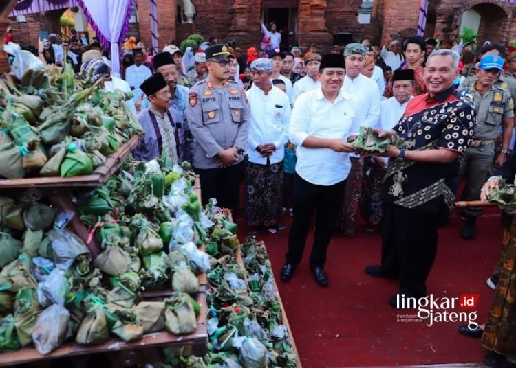 Jaga Warisan Leluhur, Pj Bupati Kudus Dukung Pelestarian Budaya Lokal 25 LESTARIKAN TRADISI: Pj Bupati Kudus Bergas Catursasi Penanggungan (depan, kanan, pakai batik) saat menerima kuliner warisan Sunan Kudus “Sego Jangkrik” dalam kegiatan tradisi budaya Ampyang Maulid di Desa Loram Kulon, Kecamatan Jati, Kabupaten Kudus, beberapa waktu lalu. (Nisa Hafizhotus. S/Lingkarjateng.id)