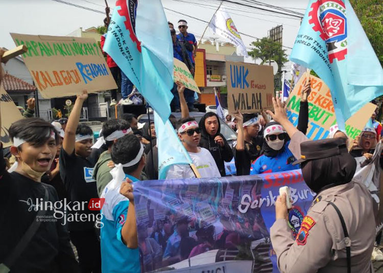 UNJUK RASA: Para buruh melakukan demonstrasi di depan gerbang Kantor Bupati Rembang sambil membentangkan tulisan keresahan para buruh terkait usulan kenaikan UMK, beberapa waktu lalu. (R.Teguh Wibowo/Lingkarjateng.id)