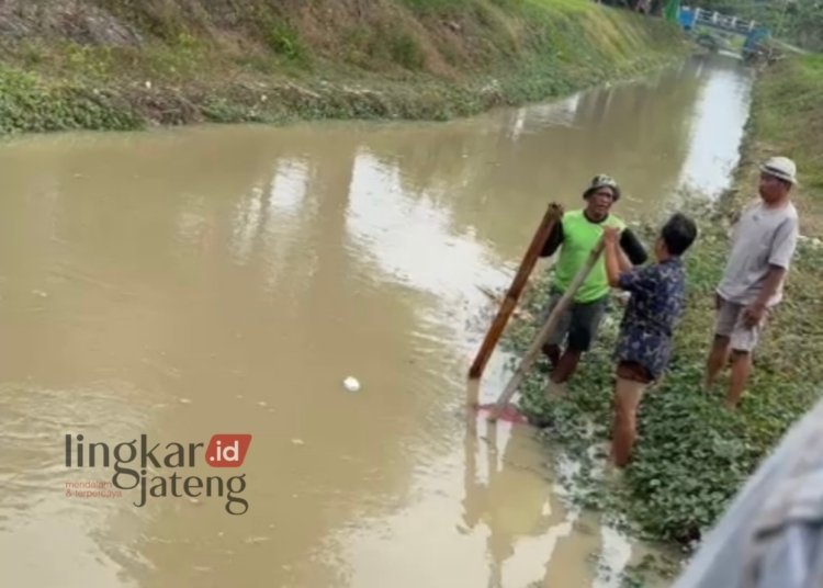 EVAKUASI: Warga setempat menahan mayat dengan alat seadanya untuk mencegah mayat terbawa arus sungai di Desa Brambang, Kecamatan Karangawen, Kabupaten Demak. (M. Burhanuddin Aslam/Lingkarjateng.id)