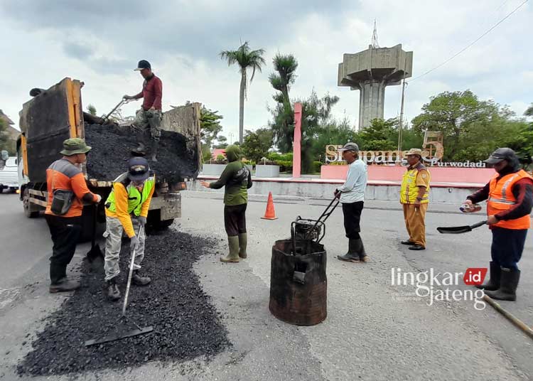 MENAMBAL: Sejumlah pekerja menambal lubang dengan aspal di jalan sekitar Simpang Lima Purwodadi untuk menyambut kedatangan Presiden Jokowi ke Grobogan. (Eko Wicaksono/Lingkarjateng.id)