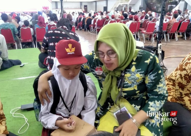 MENDAMPINGI: Kepala Bidang Pembinaan Pendidikan Dasar Dinas Pendidikan Kabupaten Blora, Titik Umiyati (kanan) mendampingi siswi bernama Tesia.(Hanafi/Lingkarjateng.id)