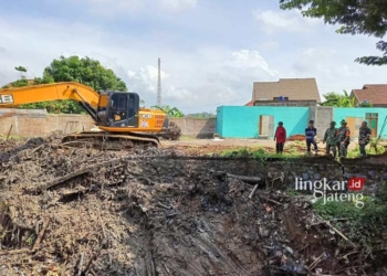 MENGERUK SAMPAH: Excavator diterjunkan untuk mengeruk sampah di Sungai Beku, Desa Mijen, Kecamatan Kaliwungu, Kabupaten Kudus. (Ihza Fajar/Lingkarjateng.id)