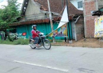 POTRET: Tampak seorang warga melintas di jalan yang terdapat APK pemilu di Blora Roboh akibat diterjang angin. (Hanafi/Lingkarjateng.id)