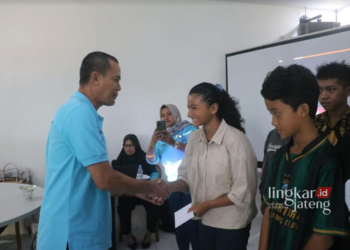 SEMRINGAH: Salah satu Pengurus Pengurus Cabang (Pengcab) Akuatik Indonesia (AI) Kabupaten Jepara Arif Darmawan saat memberikan bonus kepada para atlet dan pelatih renang berprestasi. (Tomi Budianto/Lingkarjateng.id)