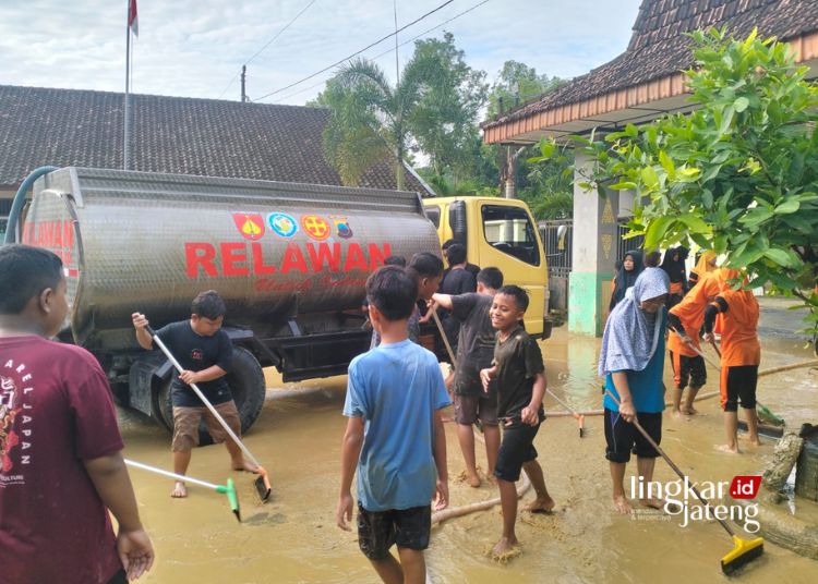 GOTONG ROYONG: Relawan Kembangjoyo bersama TNI-Polri dan siswa-siswi SDN 01 Angkatan Kidul membersihkan halaman sekolah pasca banjir, Rabu, 28 Februari 2024. (Dok. Relawan Kembangjoyo/Lingkarjateng.id)