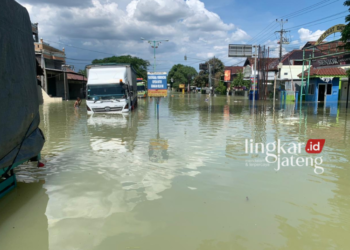 TERGENANG: Sejumlah truk besar terjebak banjir di depan Pasar Karanganyar, Demak, Kamis, 8 Februari 2024. (M Burhanudin Aslam/Lingkarjateng.id)