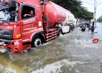 Sejumlah kendaraan nekat menerobos banjir di Jalan Pantura Karanganyar, Demak, Jumat, 16 Februari 2024. (M Burhanudin Aslam/Lingkarjateng.id)