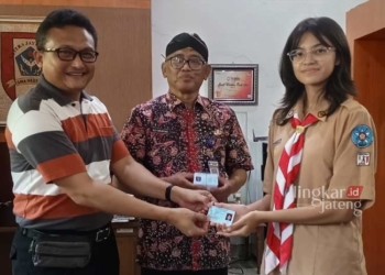 SAH PUNYA HAK PILIH: Kepala Disdukcapil Kabupaten Pati (kiri) menyerahkan e-KTP kepada Kepala SMAN 1 Pati Suhartono dan perwakilan siswa di sekolah setempat. (Setyo Nugroho/Lingkarjateng.id)