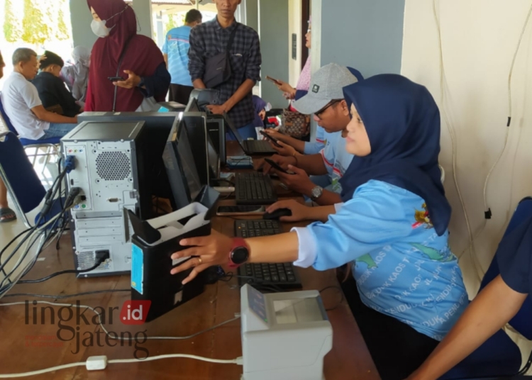 POTRET: Petugas Dispendukcapil Kendal saat melayani warga untuk melakukan rekam e-KTP di stadion Kendal, pada Minggu, 11 Februari 2024. (Robison/Lingkarjateng.id)
