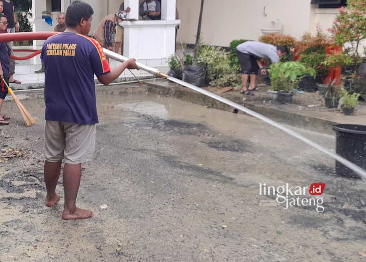 BERSIH-BERSIH: Personel Damkar membersihkan area Setda Grobogan dari lumpur pascabanjir. (Eko Wicaksono/Lingkarjateng.id)