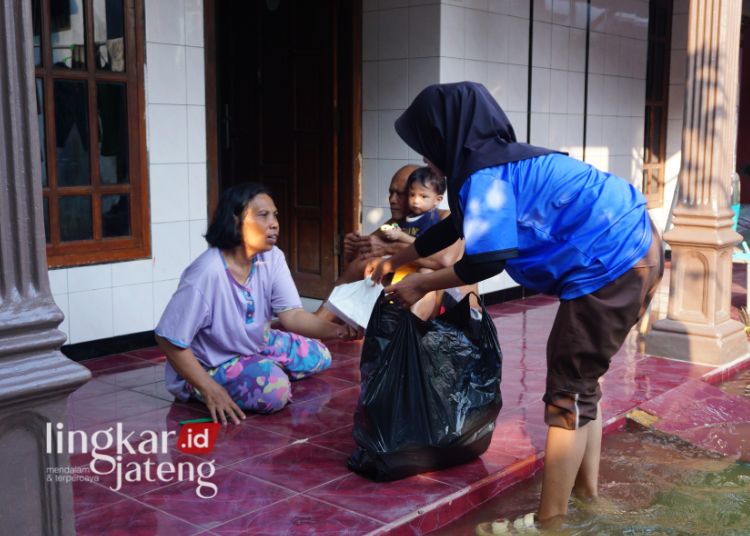 BERJIWA SOSIAL: Seorang siswa SMK BTB Juwana, Pati saat memberikan bantuan nasi bungkus untuk warga terdampak banjir di Desa Bumirejo Pencikan, Kecamatan Juwana, Kabupaten Pati, belum lama ini. (SMK BTB Juwana/Lingkarjateng.id)