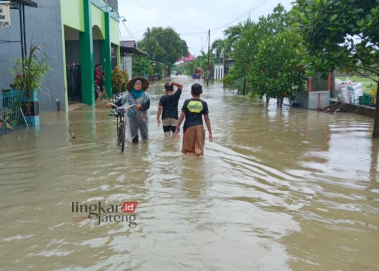 BANJIR: Tampak warga sedang melintasi genangan air banjir di Desa Temulus, Kecamatan Mejobo, pada Kamis, 14 Maret 2024. (Nisa HS/Lingkarjateng.id)