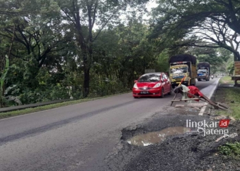 BERLUBANG: Lubang di jalan Purwodadi-Semarang dipasangi rambu berupa kayu oleh warga Desa Bringin, Kecamatan Godong, Kabupaten Grobogan. (Eko Wicaksono/Lingkarjateng.id)