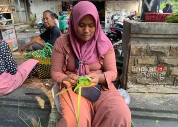 FOKUS: Seorang pedagang tengah membuah selongsong ketupat mendekati lebaran ketupat. Bahkan stok janur kuning kini berkurang pesat. (M Burhanuddin Aslam/Lingkarjateng.id)
