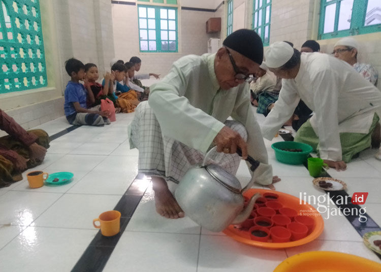 SUGUHKAN KOPI: Seorang warga tengah menyeduh kopu untuk warga dan musafir yang akan berbuka di Masjid Layur, belum lama ini. (Rizky Syahrul Al-Fath/Lingkarjateng.id)