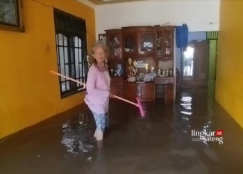 Warga membersihkan rumah yang terendam banjir. (Hesty Imaniar/Lingkarjateng.id)