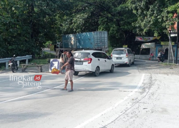 KONDUSIF: Tukang Gebyok sedang mengatur jalan karena sedang ada perbaikan jalan di Jalan Raya Purwodadi-Solo, Grobogan, Jumat 4 Mei 2024. (Eko Wicaksono/Lingkarjateng.id)