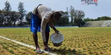 Pekerja memberikan garis pada lapangan Stadion Krida Bhakti Purwodadi dengan warna chat putih. (Eko Wicaksono/Lingkarjateng.id)