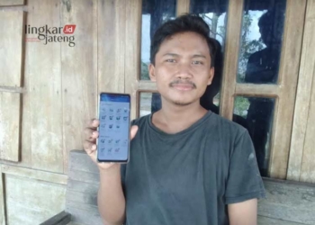Eko Budiono (25), laki-laki asal Desa Klecoregonang, Kecamatan Winong, Kabupaten Pati, menunjukkan Mobile JKN miliknya. (Setyo Nugroho/Lingkarjateng.id)
