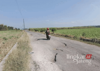 Pengendara motor saat melintasi Jalan Alternatif Winong-Pati via Desa Bringinwareng yang dalam kondisi rusak berat dan belum ada perbaikan. (Arif Febriyanto/Lingkarjateng.id)