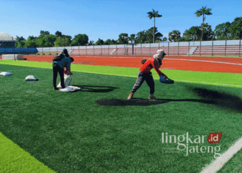Penaburan granule di rumput sintetis lapangan Stadion Joyokusumo Pati pada Senin, 15 Juli 2024. (Setyo Nugroho/Lingkarjateng.id)