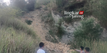 Anggota polisi memperlihatkan lokasi lansia tewas tertimpa batu di tambang batu kapur ilegal di Grobogan. (Dok. Lingkarjateng.id)