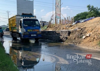 Pengendara sedang melintas di jalan yang basah akibat air yang merembes dari tanggul Sungai Jratun di depan Masjid Besar Al-Madinah Karanganyar, Kabupaten Demak. (M. Burhanuddin Aslam/Lingkarjateng.id)