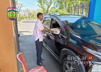 Petugas penjaga pintu masuk objek wisata Pantai Kartini Jepara saat menyerahkan tiket secara manual kepada pengunjung pada Kamis, 19 September 2024. (Muhammad Aminudin/Lingkarjateng.id)