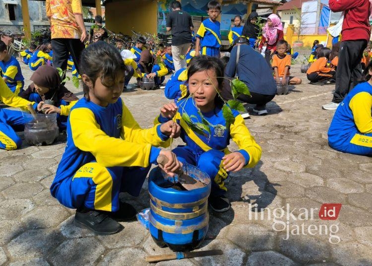 Para murid SD Negeri 2 Bandengan saat melakukan penanaman bibit pohon yang diberikan oleh DLH Kendal. (Arvian Maulana/Lingkarjateng.id)
