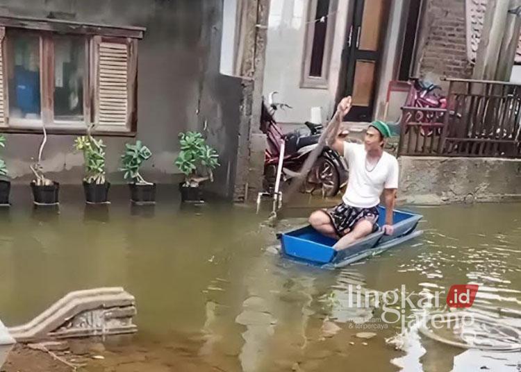 Seorang warga Desa Gebang, Kecamatan Bonang, Kabupaten Demak, menyeberang menggunakan perahu tong buatan akibat banjir tak kunjung surut. (Dok. Pribadi/Lingkarjateng.id)