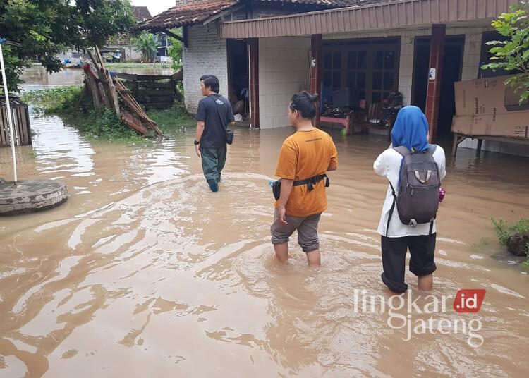 Warga Desa Doropayung, Kecamatan Juwana, Kabupaten Pati, saat melintasi banjir yang melanda wilayah setempat pada Kamis, 30 Januari 2025. (Setyo Nugroho/Lingkarjateng.id)