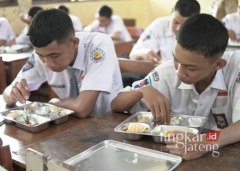 Dua siswa SMKN Pati tengah menyantap makanan program makan bergizi gratis (MBG) pada Senin, 13 Januari 2025. (Setyo Nugroho/Lingkarjateng.id)
