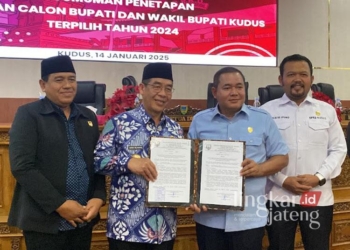 Pj. Bupati Kudus, Herda Helmijaya, dan Ketua DPRD Kudus, Masan, menunjukkan berita acara rapat paripurna penetapan Sam'ani-Bellinda sebagai pasangan calon bupati dan wakil bupati terpilih pada Selasa, 14 Januari 2025. (Mohammad Fahtur Rohman/Lingkarjateng.id)