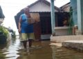 Salah seorang warga Doropayung, Kecamatan Juwana, Kabupaten Pati, sedang beraktivitas di tengah banjir yang melanda desa setempat pada Senin sore, 17 Februari 2025. (Setyo Nugroho/Lingkarjateng.id)