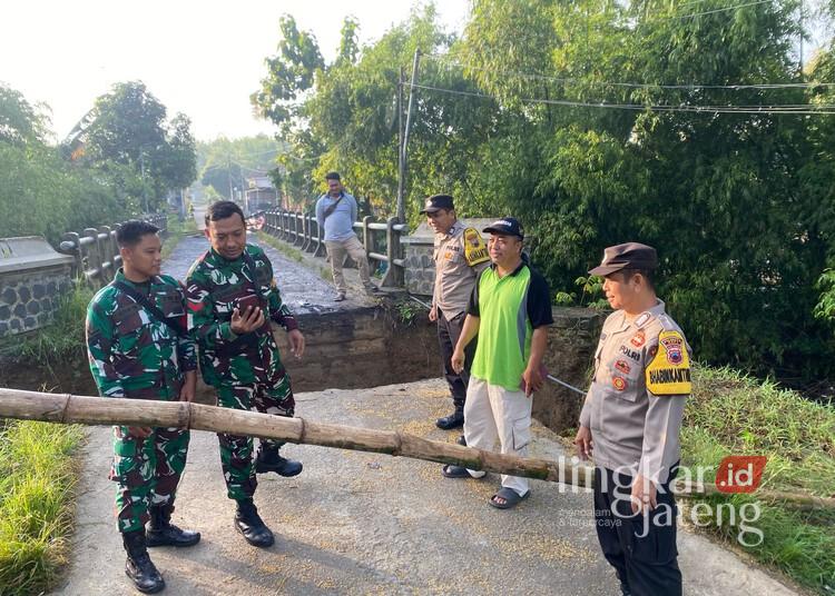 Anggota Polsek dan Koramil Pucakwangi meninjau jembatan Desa Pelemgede, Kecamatan Pucakwangi, Kabupaten Pati, yang ambrol, Minggu, 16 Februari 2025. (Setyo Nugroho/Lingkarjateng.id)