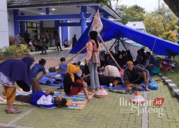 Puluhan petani Desa Pundenrejo, Kecamatan Tayu, Kabupaten Pati, istirahat di dalam tenda yang didirikan di depan Kantor Agraria Tata Ruang/Badan Pertanahan Nasional (ATR/BPN) Pati sebagai aksi protes atas polemik lahan pada Senin, 10 Februari 2025. (Setyo Nugroho/Lingkarjateng.id)