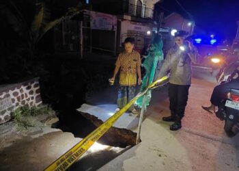 Anggota Polsek Tambakromo memasang tanda bahaya rambu-rambu dan garis polisi di jembatan longsor, Dukuh Sebetan, Desa Sinomwidodo, Kecamatan Tambakromo, Kabupaten Pati, Rabu, 19 Februari 2025. (Dok. for Lingkarjateng.id)