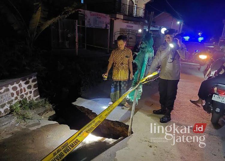 Anggota Polsek Tambakromo memasang tanda bahaya rambu-rambu dan garis polisi di jembatan longsor, Dukuh Sebetan, Desa Sinomwidodo, Kecamatan Tambakromo, Kabupaten Pati, Rabu, 19 Februari 2025. (Dok. for Lingkarjateng.id)